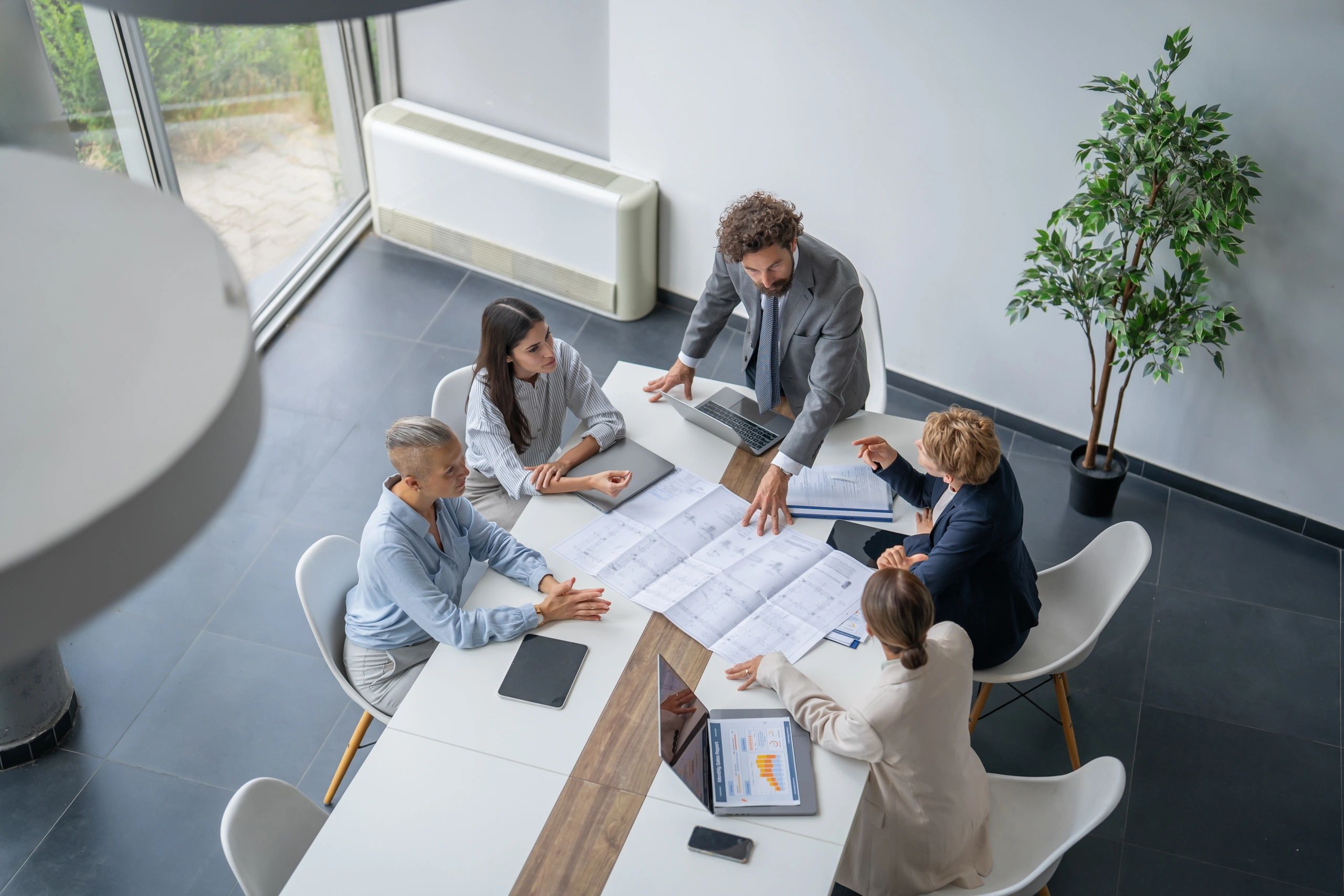 Business team analyzing blueprints during meeting in modern office